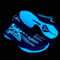 a pair of blue and black shoes with white soles on a black background,