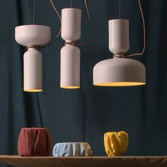 three lamps hanging over a table with cloths on it