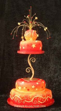 a three tiered cake with stars and swirls on the top is lit up