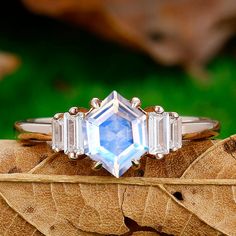 three stone ring sitting on top of a leaf