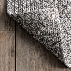 a gray and white rug on top of a wooden floor