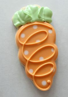 a cookie shaped like a carrot on top of a white table with polka dotes