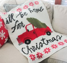 a red truck with a christmas tree on it is sitting on a couch next to pillows