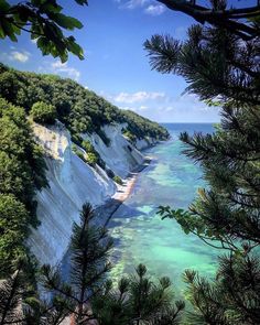 the water is crystal blue and clear with green trees on both sides, as well as white cliffs in the background