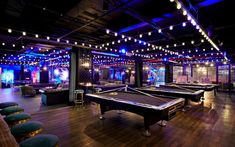 a room with pool tables, couches and lights on the ceiling is lit up