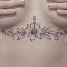 a woman's chest with flowers and leaves on it, as well as her hands