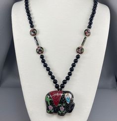 This bold necklace features a cloisonné enamel elephant pendant, hanging from a strand of black onyx and cloisonné beads. The safety clasp and the tiny gold accent beads are 14 karat gold. The elephant pendant measures about 2 inches across, and the strand measures about 32 inches long. This necklace dates from the 1980s, and it is in very good, clean original condition. Please see photos for details. US buyers only, please. Free shipping. Bold Necklace, Elephant Necklace, Elephant Pendant, Cloisonne Enamel, Onyx Bead, Gold Accent, Pink Rhinestones, Gold Accents, Earings Piercings