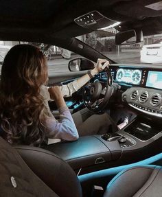 a woman sitting in the driver's seat of a mercedes vehicle with her hands on the steering wheel