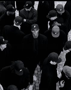 a group of men standing next to each other on top of a brick floor covered in hats