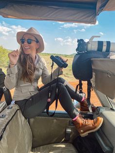 a woman is sitting in the back of a vehicle with her camera and tripod