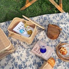 an outdoor picnic with food and drinks on the blanket in front of it, along with two wooden chairs