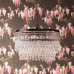 a chandelier hanging from a ceiling with pink flowers on the wall behind it