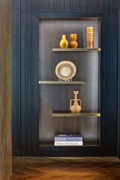 a shelf with some vases and plates on it in a room that has wood flooring