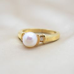 This classic pairing features a white Akoya pearl set in 14K yelloow gold with a diamond on either side of the pearl setting. Akoya pearls are luxurious pearls found in the Japan and China regions. They are renowned for their brilliant luster and their perfect roundness. ADDITIONAL INFORMATION: Pearl Size: approx.7.3 diameter freshwater pearls Diamonds: .05TW round diamonds Clasp Material: 14K Yellow Gold Band Width: 2.2mm Ring Size: Current size 7 *During the sale, ring sizing is not included. White Akoya Pearl Timeless Ring, Timeless Pearl White Pearl Ring For Anniversary, Timeless White Akoya Pearl Ring, Classic White Pearl Ring With Drop Detail, Classic White Pearl Ring With Pearl Charm, Classic White Pearl Ring With Charm, Timeless Pearl White Pearl Ring, Classic White Pearl Ring, Timeless Akoya Pearl Ring For Anniversary