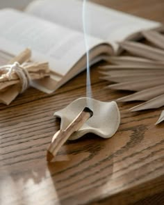 an open book on top of a wooden table next to a pair of scissors and string