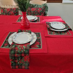 the table is set with red and green plaid napkins, place mats, and white plates