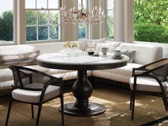 a living room filled with furniture and a chandelier hanging from the ceiling over a table