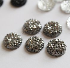 several black and silver glittered buttons on a white surface