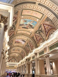 people are walking around in the lobby of a building with painted ceilings and ceiling murals