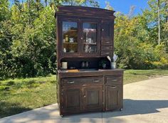 an old wooden china cabinet sitting on top of a sidewalk