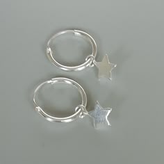 A PAIR of sterling silver hoops. Comes with a detachable tiny and delicate star charm. The charm is multipurpose and can be used with a neck or bracelet chain too. Dimension: Hoop- 12 x 1.5 mm Charm- 5 x 5 mm Drop length- 18 mm Price listed is for a PAIR of hoops. These earrings are made of 925 hypoallergenic sterling silver and comes with a 925 stamp. Can be packaged in a gift box. I can include a personal message from you if needed You are welcome to contact me at... bhavnakwintra1956@gmail.co Silver Star Charm Huggie Earrings, Silver Star Shaped Huggie Earrings With Charm, Silver Star Huggie Earrings For Everyday, Small Hoop Sterling Silver Earrings With Star Charm, Silver Huggie Earrings With Star Charm For Gift, Hypoallergenic Sterling Silver Star Hoop Earrings, Sterling Silver Huggie Earrings With Star Charm For Everyday, Silver Huggie Earrings With Star Charm As Gift, Hypoallergenic Star-shaped Sterling Silver Hoop Earrings