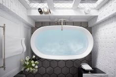 an oval bathtub hanging from the ceiling in a bathroom with white walls and black tiles