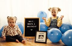 two toddlers sitting on the floor with balloons in front of them and a sign that says wait what's a brother?