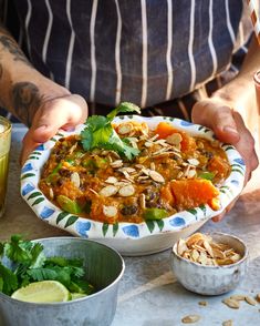 a person holding a bowl filled with food next to bowls of vegetables and other foods