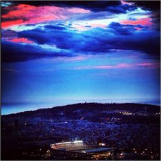 an aerial view of a city at night with clouds in the sky and lights on