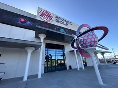 an outside view of a building with a large object in the foreground and a sign that says atomic golf on it