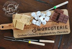 a cutting board that has some crackers and marshmallows on it with chocolate