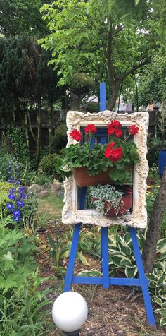 a blue easel with red flowers in it and a white ball on the ground