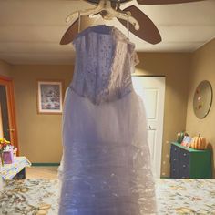 a dress is wrapped in plastic and hanging from a ceiling fan on a bed room table