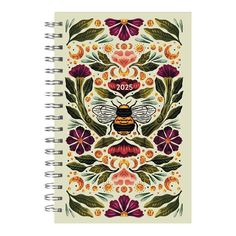 a spiral notebook with an image of a bee and flowers on the front, surrounded by leaves