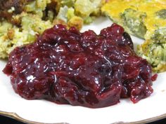 a white plate topped with cranberry sauce next to broccoli and other foods