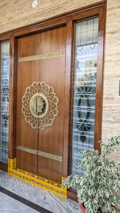 a large wooden door sitting inside of a building next to a potted green plant