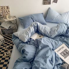 an unmade bed with blue sheets and pillows