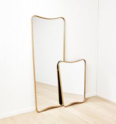 a mirror sitting on top of a wooden floor next to a white wall in a room