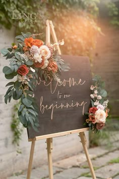 an easel with flowers and greenery on it that says welcome to our beginning