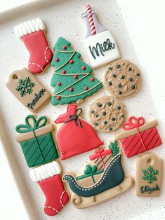 decorated cookies in the shape of christmas trees, stockings and gifts on a white tray