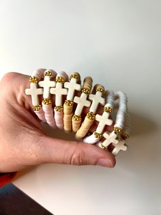 a person is holding several different types of bracelets with crosses on them, all in white and gold