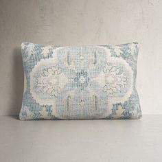 a blue and white decorative pillow sitting on top of a gray table next to a wall