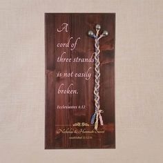 a wooden plaque with a cross on it that says, a cord of three strands is not easily broken