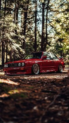 a red car is parked in the woods