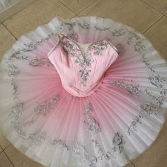 a pink ballerina's tutu is sitting on the floor in front of a tile floor