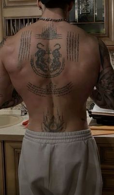 a man with tattoos on his back standing in front of a sink