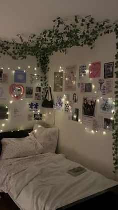 an unmade bed in a room with lights on the wall and pictures above it