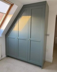 an attic bedroom with blue painted closets and white carpeted flooring in front of a skylight