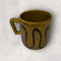 a brown and black coffee cup sitting on top of a white table next to a wall