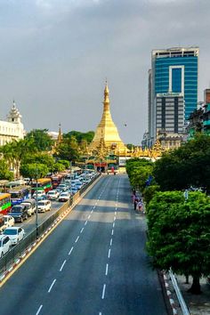 a city street filled with lots of traffic next to tall buildings and trees on both sides